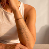Geometrische madelief & kersenbloesem tatoeage